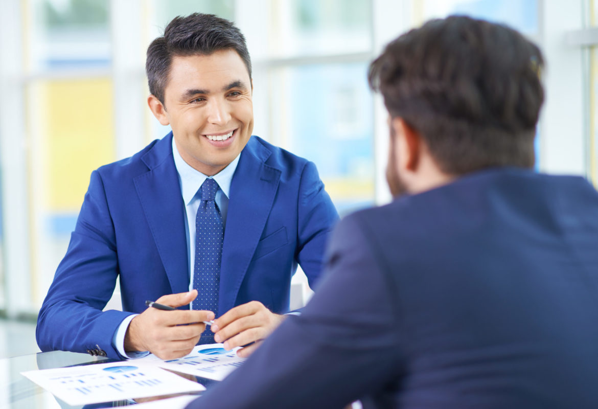 Image of handsome businessman in suit communicating with his colleague at meeting